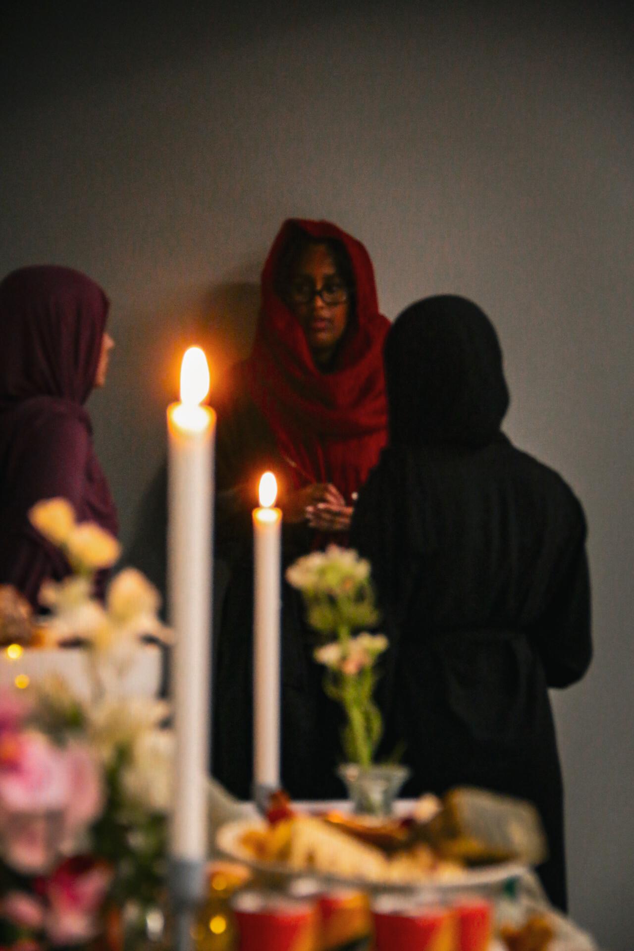 Women in conversation behind candlelight and flowers
