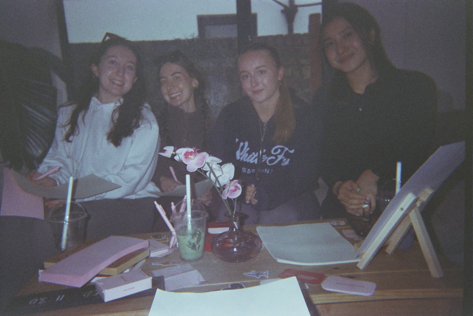 Four women smiling together behind a table of creative materials